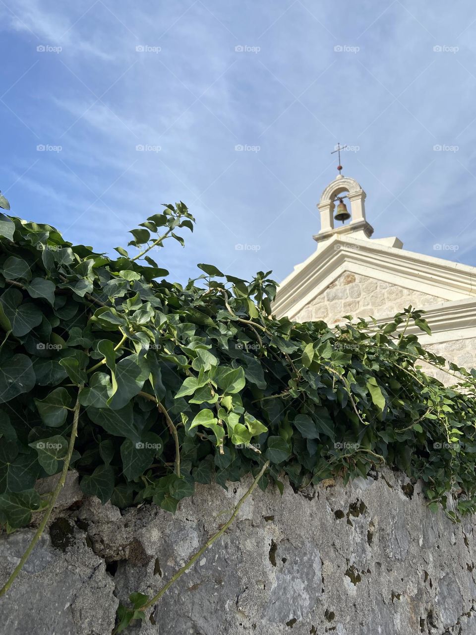 Stone wall with ivy near small church.