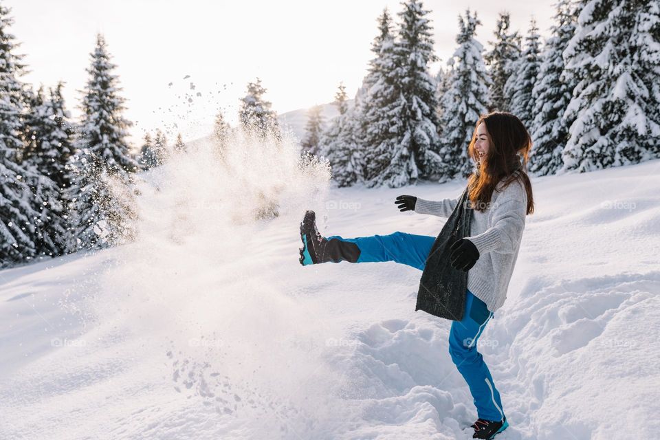 beautiful woman playing in the snow at sunset time