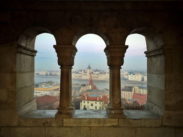The Hungarian Parliament between pillars of a castle across the river separating Buda from Pest  