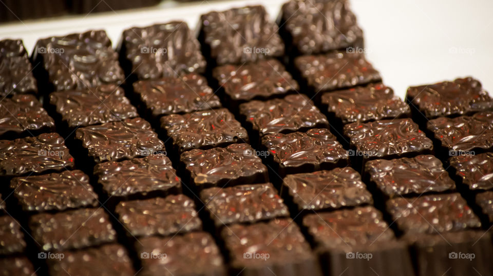 Beautiful gourmet chocolate squares on white porcelain tray    Decadent dark chocolate dessert photography background with selective focus 