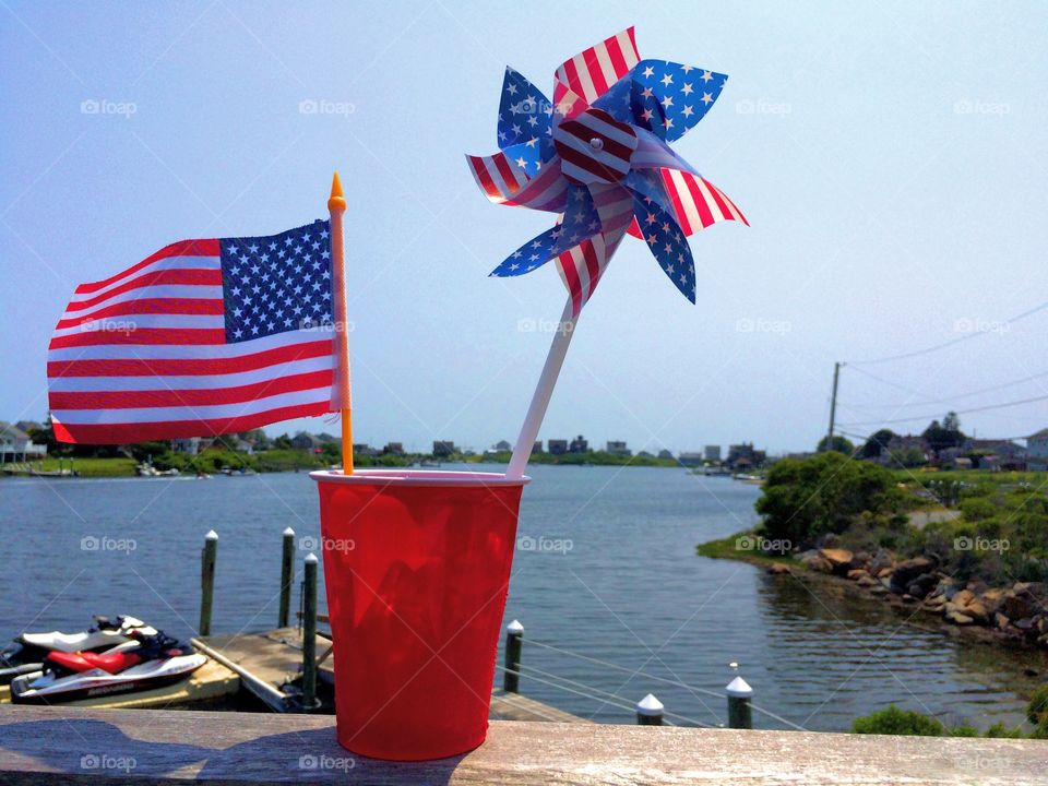 Stars and Stripes 1. Happy Fourth of July!
Small American flag and pinwheel in a red cup, with a small marina in the background.