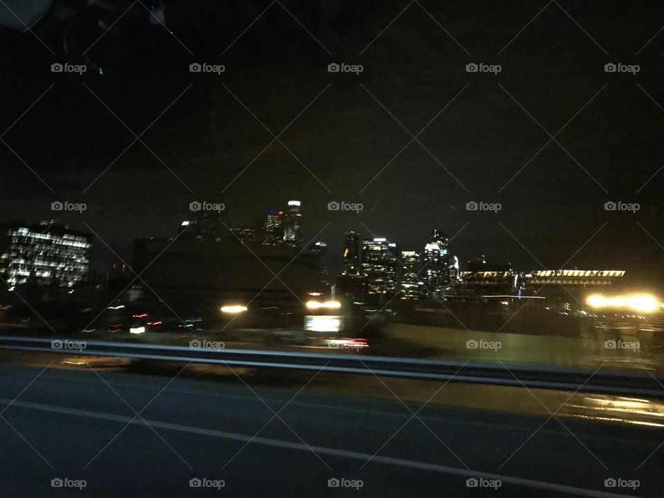 Blurry downtown Los Angeles skyline at night from freeway