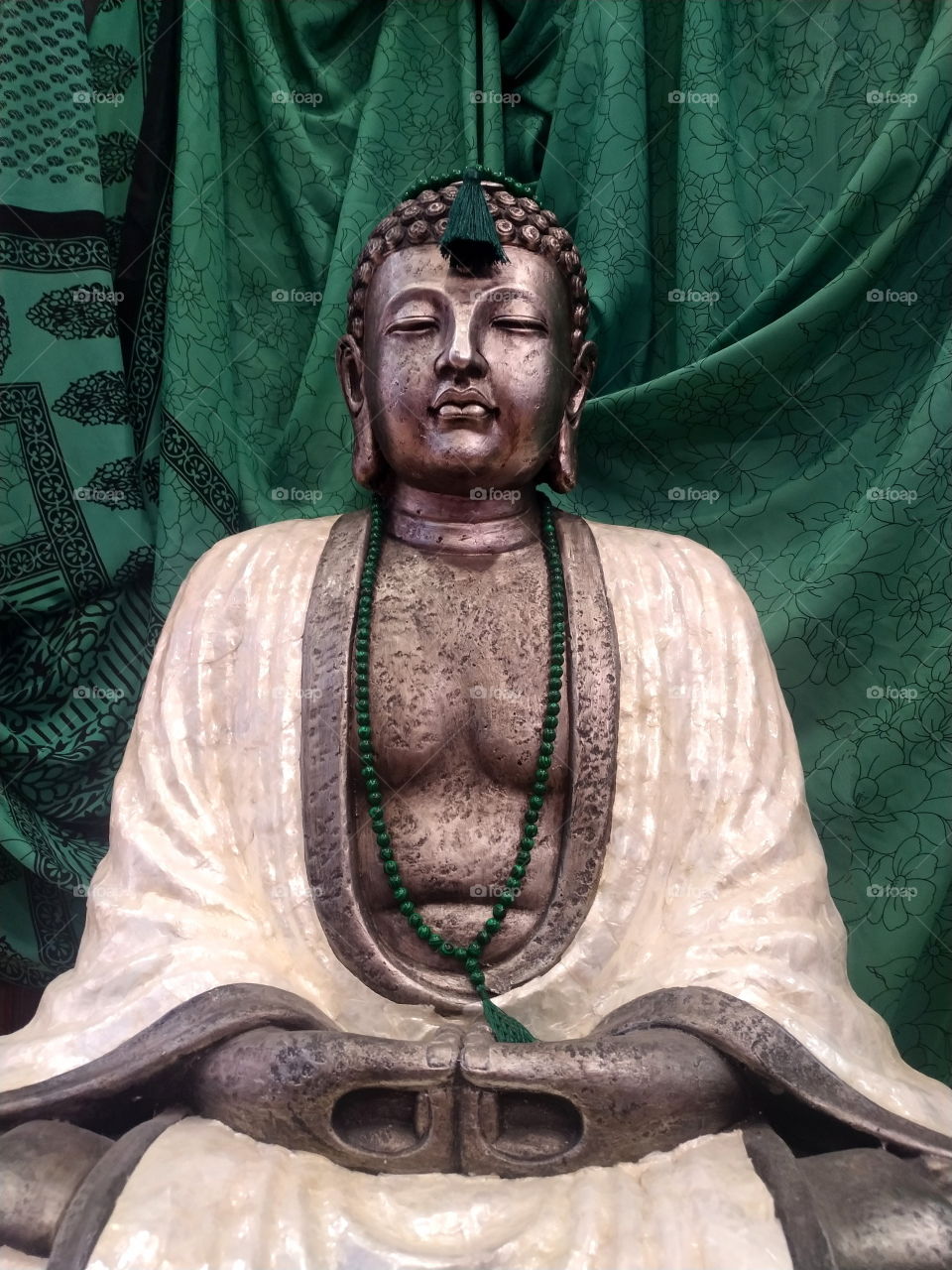 a figurine of a buddha in white robes made of natural mother-of-pearl