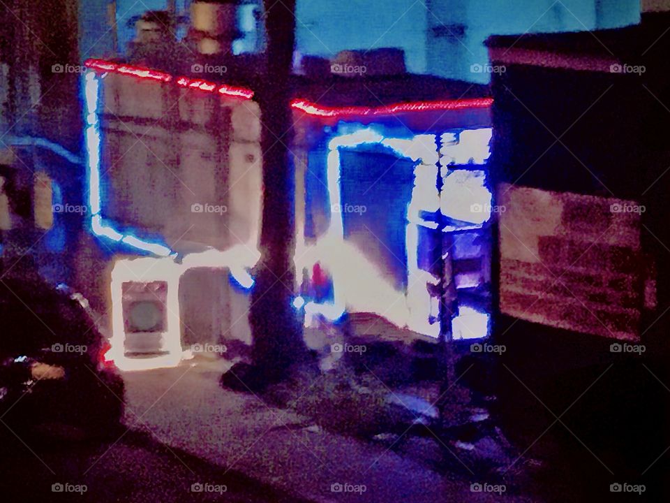 The 24 hour takeout food vendor stand illuminated by colorful neon lights in the parking lot underneath the Pulaski Bridge in Long Island City, Queens, NY seen from above ascending the staircase to the bridge. Photo 2020. Hypnotic Productions