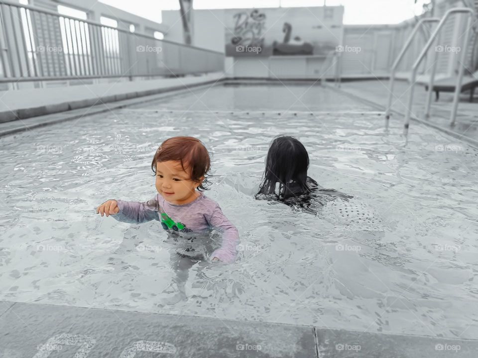 happy asian sisters enjoying playing in the pool