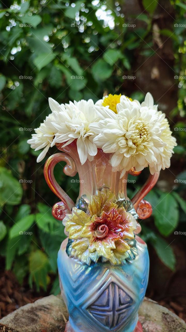 Beautiful white flowers in a colourful flowerpot with a flower sculpture, Flowers in a vase, colourful vase, white flowers in a vase