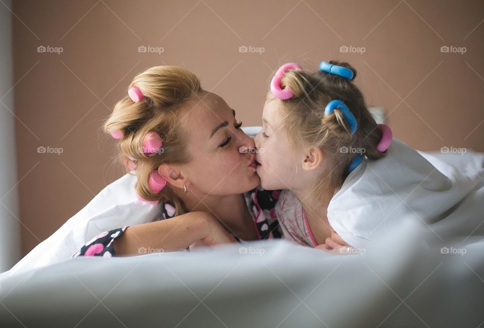 beautiful mother and her daughter spend time together at home. Gentle and warm attitude, girls have fun, hug and make themselves beautiful