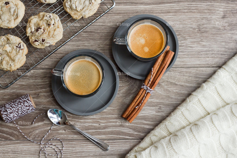 Two cups of fresh espresso styled with cookies and a warm blanket