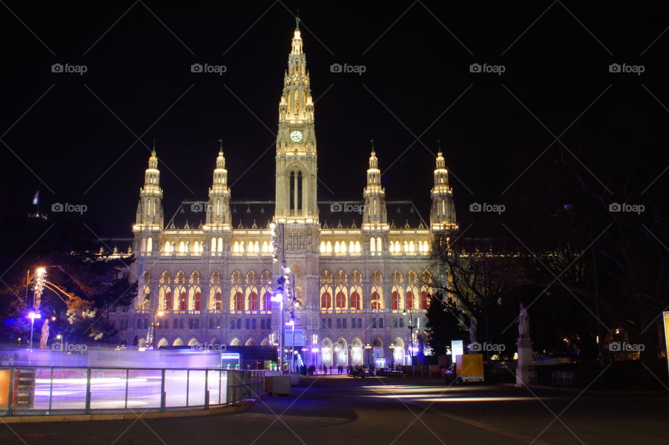 The Vienna ice rink in the evening a long exposure shot with long shadows of people and colourful lighting spots in early spring. People whose faces cannot recognize, skating to the music circle and having fun