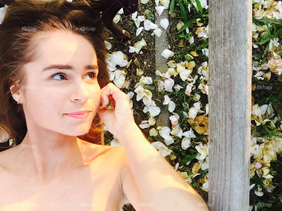 Portrait of woman surrounded by white rose petals