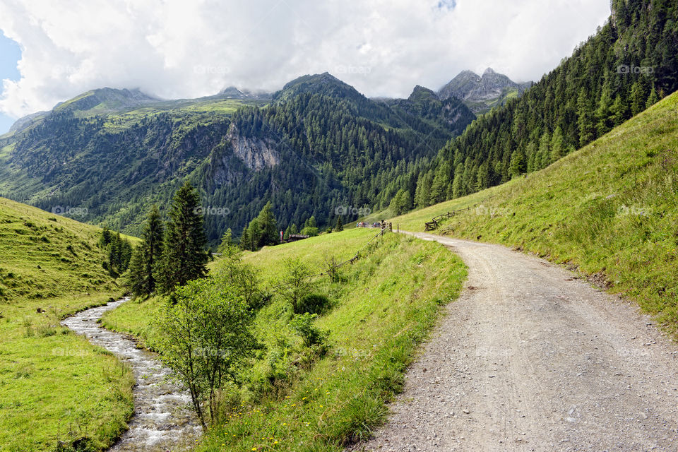 European alps landscape. Stream flowing though Schwarzachtal valley in zillertal alps. path keading along. Austria.