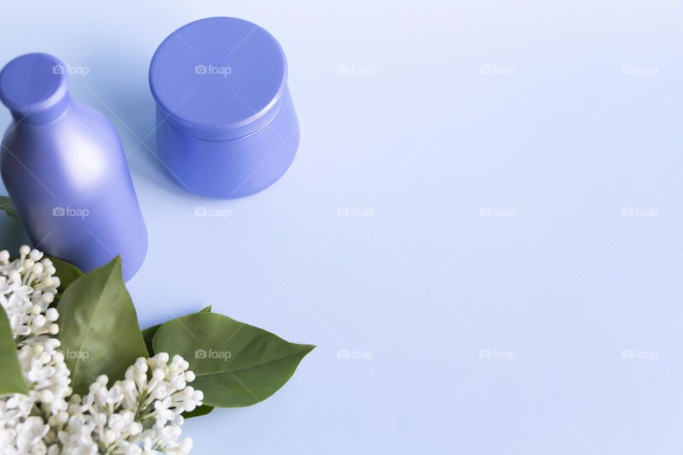 Spring, white fragrant lilac with green leaves.  and jars with cosmetic cream and product.