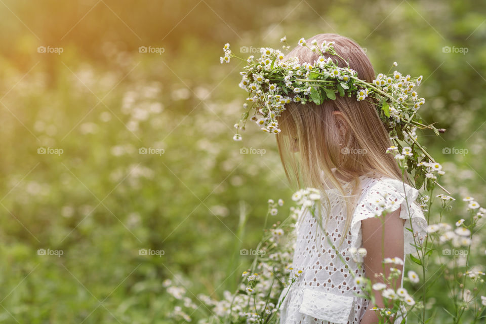 Little girl with blonde hair on the meadow 