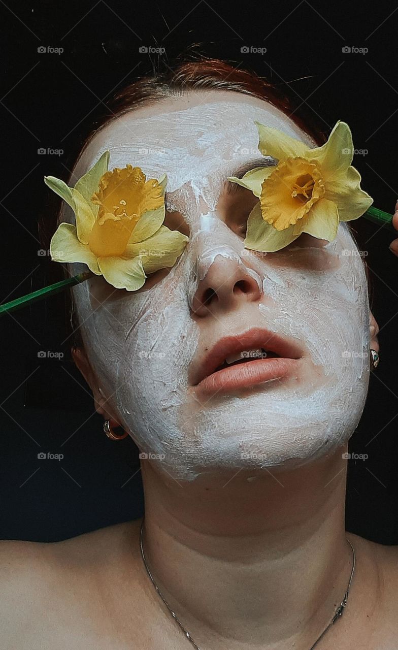 Portrait of a girl with a mask on her face and flowers instead of eyes