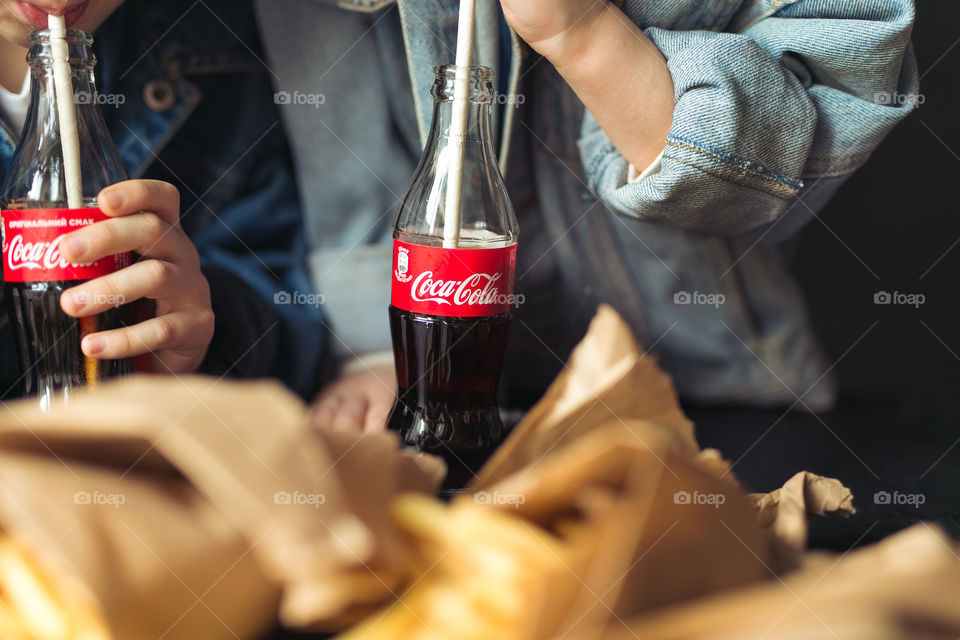 cute guys, brother and sister, move out, rejoice, spend time together and drink Coca-Cola.  children are dressed in denim clothes, black background.  bottles with coca-cola glass