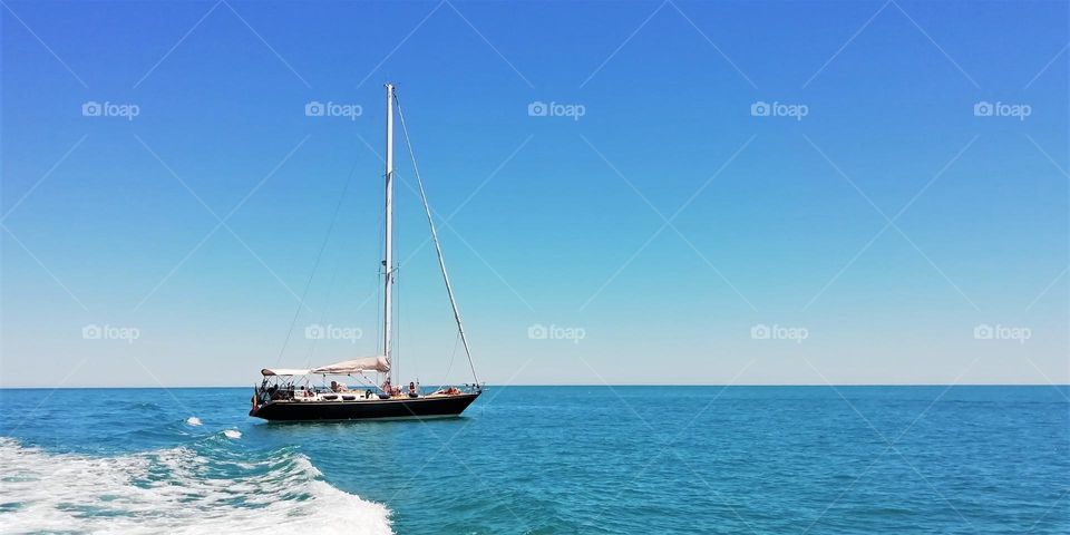 Blue sky, blue sea. On a hot summer day, it's so wonderful to sail on a yacht in the calm sea.