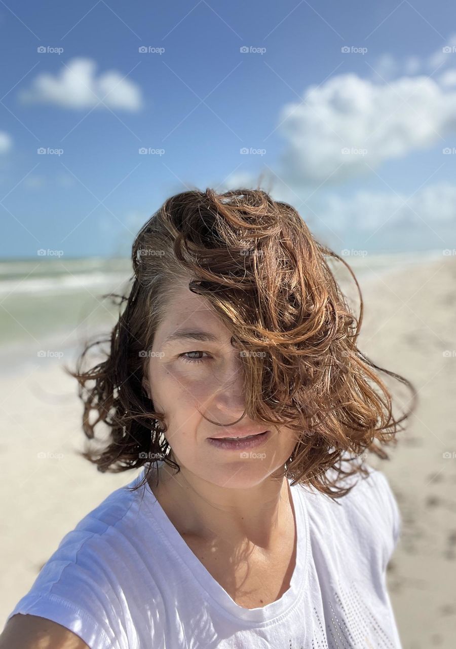 Woman with brown hair self portrait against beach 