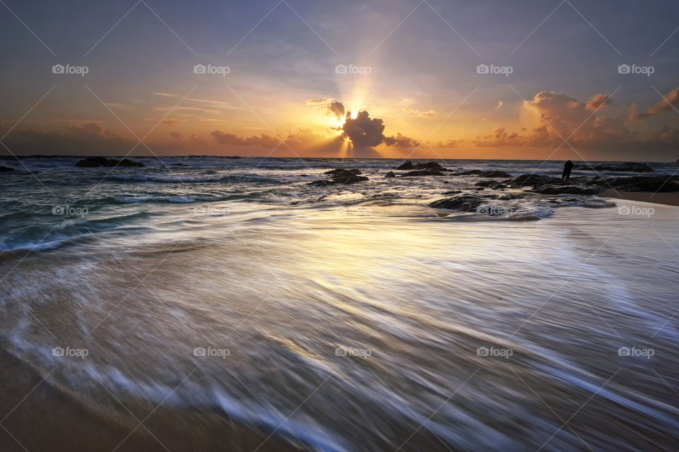 Sunrise over the beach with motion waves and dramatic skies