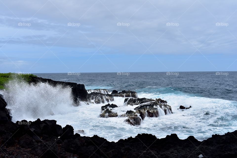 Big waves and splashes on an outcropping of lava rock along the sea cliffs on the Big Island of Hawaii