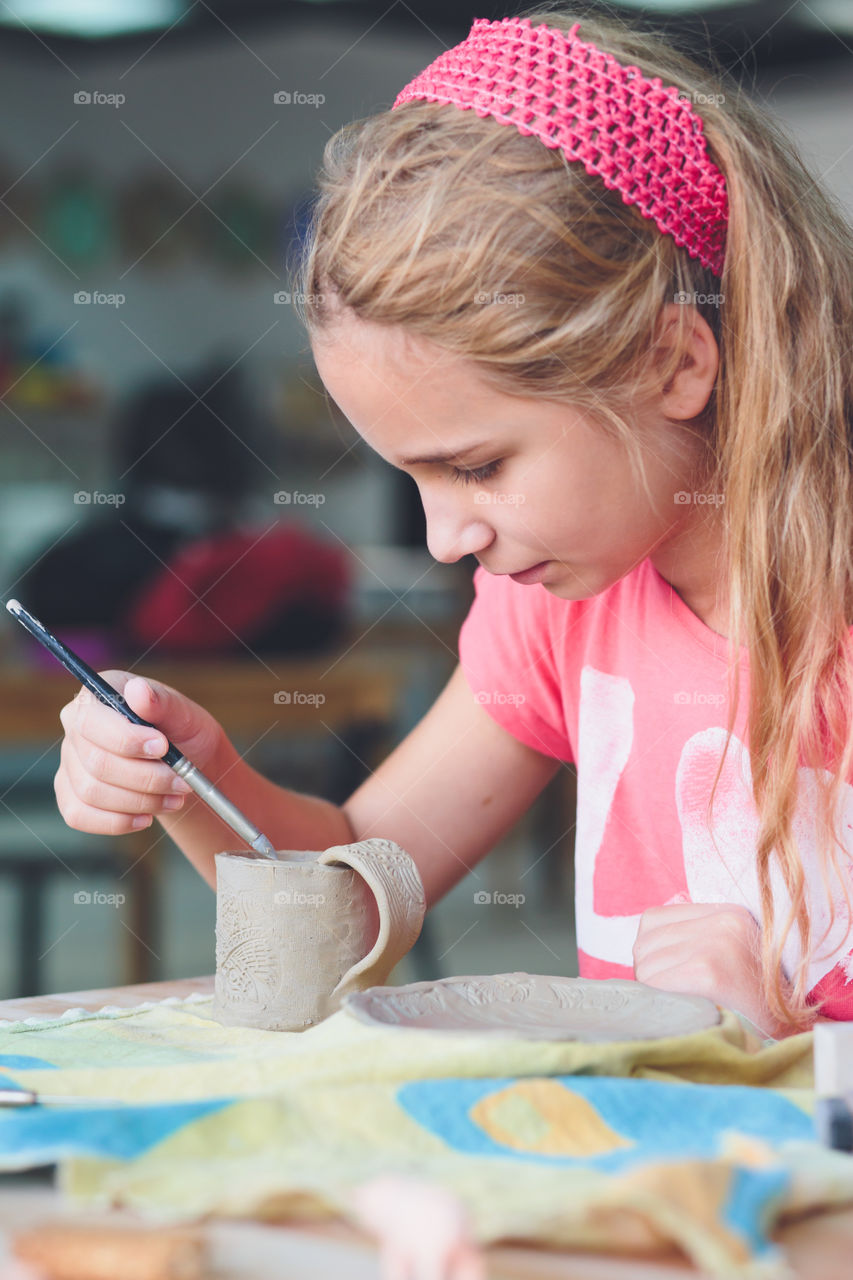 Girl carving on clay cup