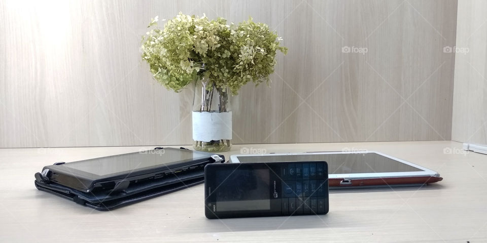 Phone and 2 gadgets are on a wood white table