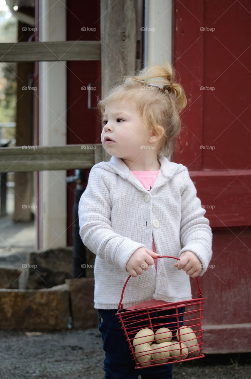 Cute girl holding eggs in basket