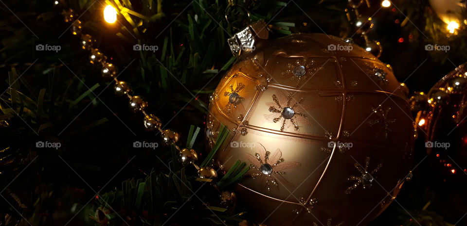 A christmas ball with tiny diamond and a beautiful chain in a christmas tree.