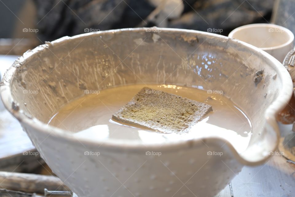 A big bowl with clay water  to work with in the pottery 