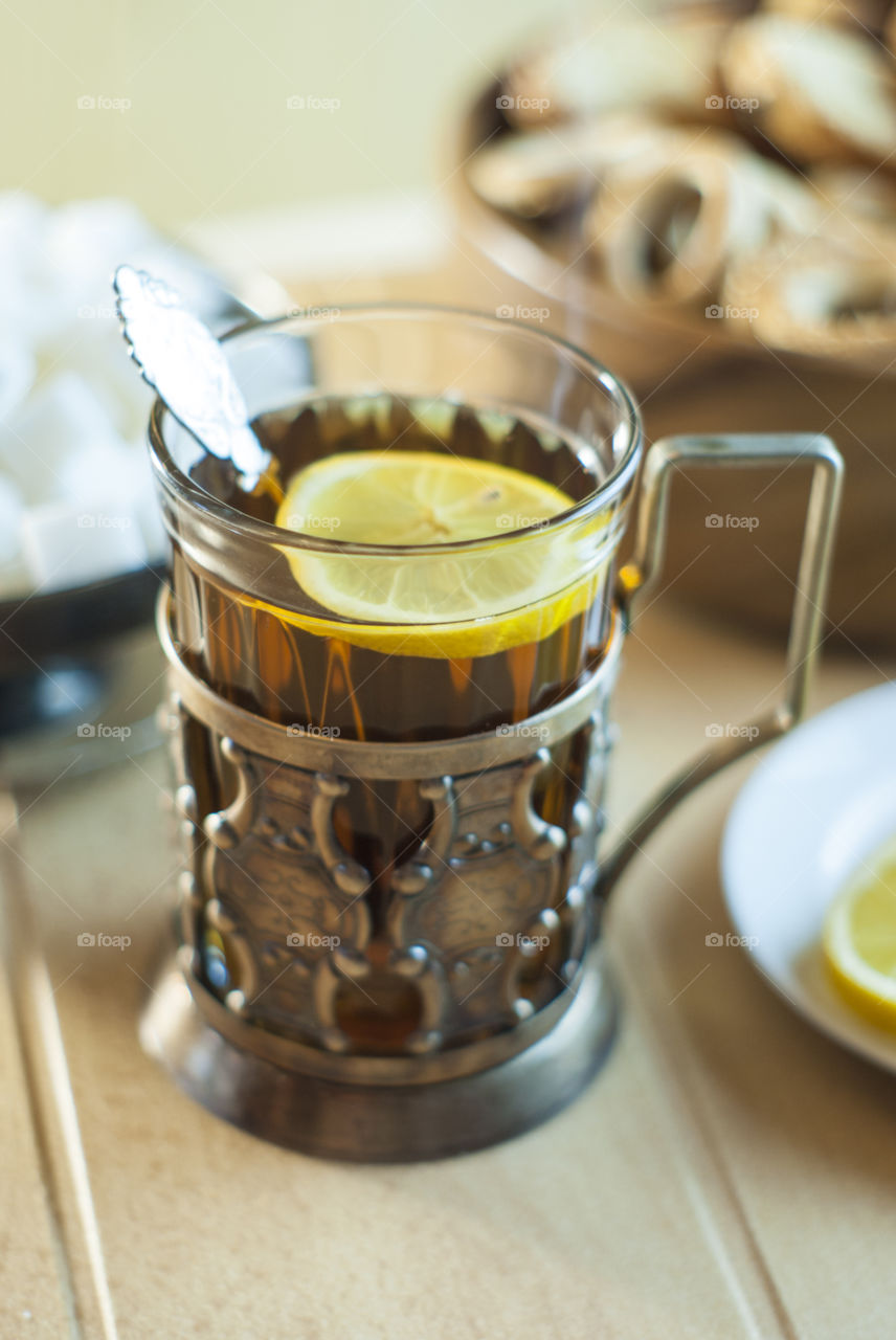 Tea in a glass in an old cup holder with drying and lemon