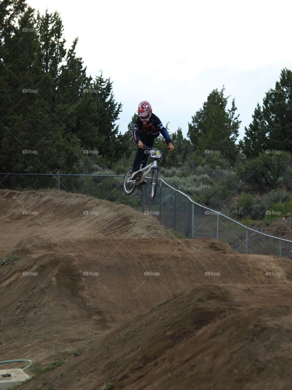 A BMX racer jumps a hill and flies several feet off of the ground. 