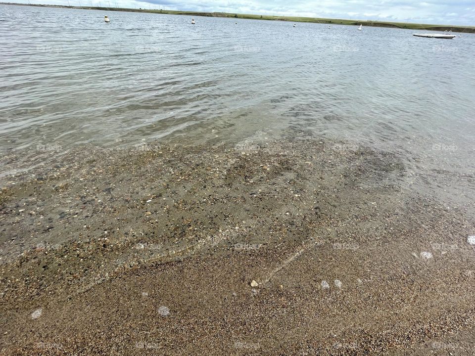 Man made lake, called Rattlesnake dam, close to Medicine Hat,Alberta, Canada, is good for fishing, boating, swimming, camping, and this sandy brown beach for suntanning on this sunny summer day