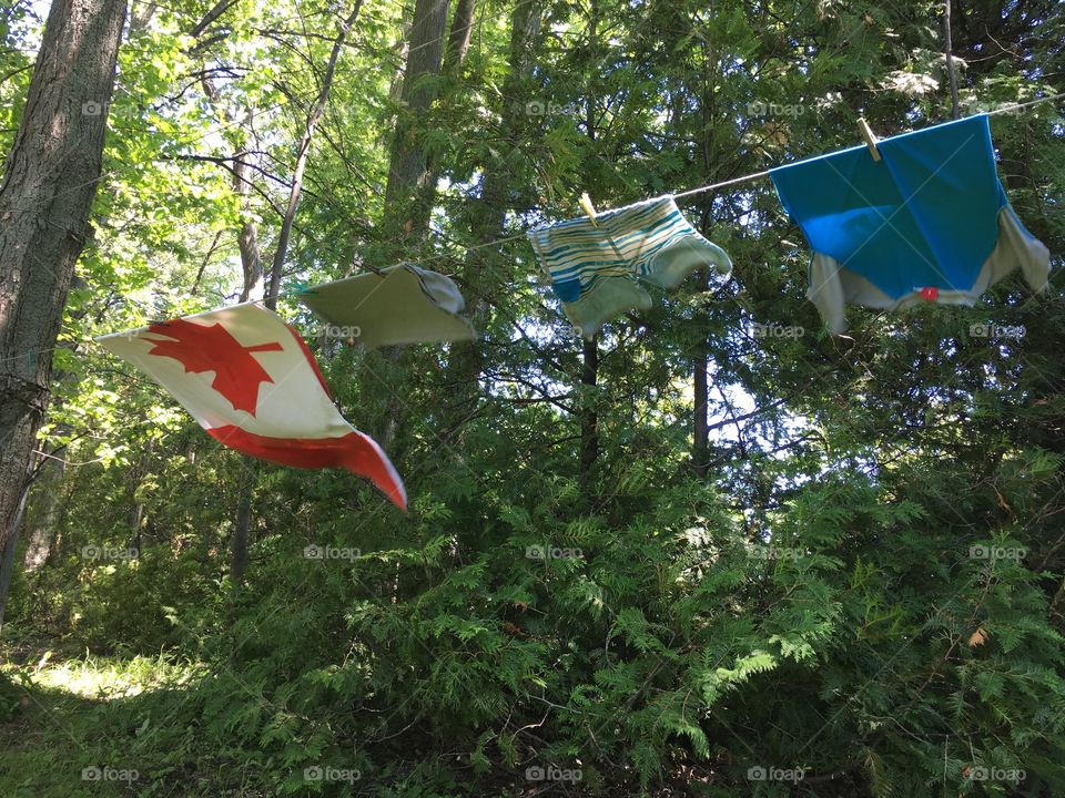 Camping in the forest Canadian flag on clothes line with swimming trunks and t-shirt conceptual summer vacation adventure travel off the beaten path in Canada photography