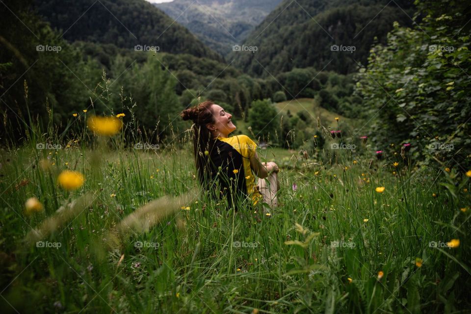 Woman enjoying the view while hiking in a beautiful meadow with colorful flowers at the beginning of summer.