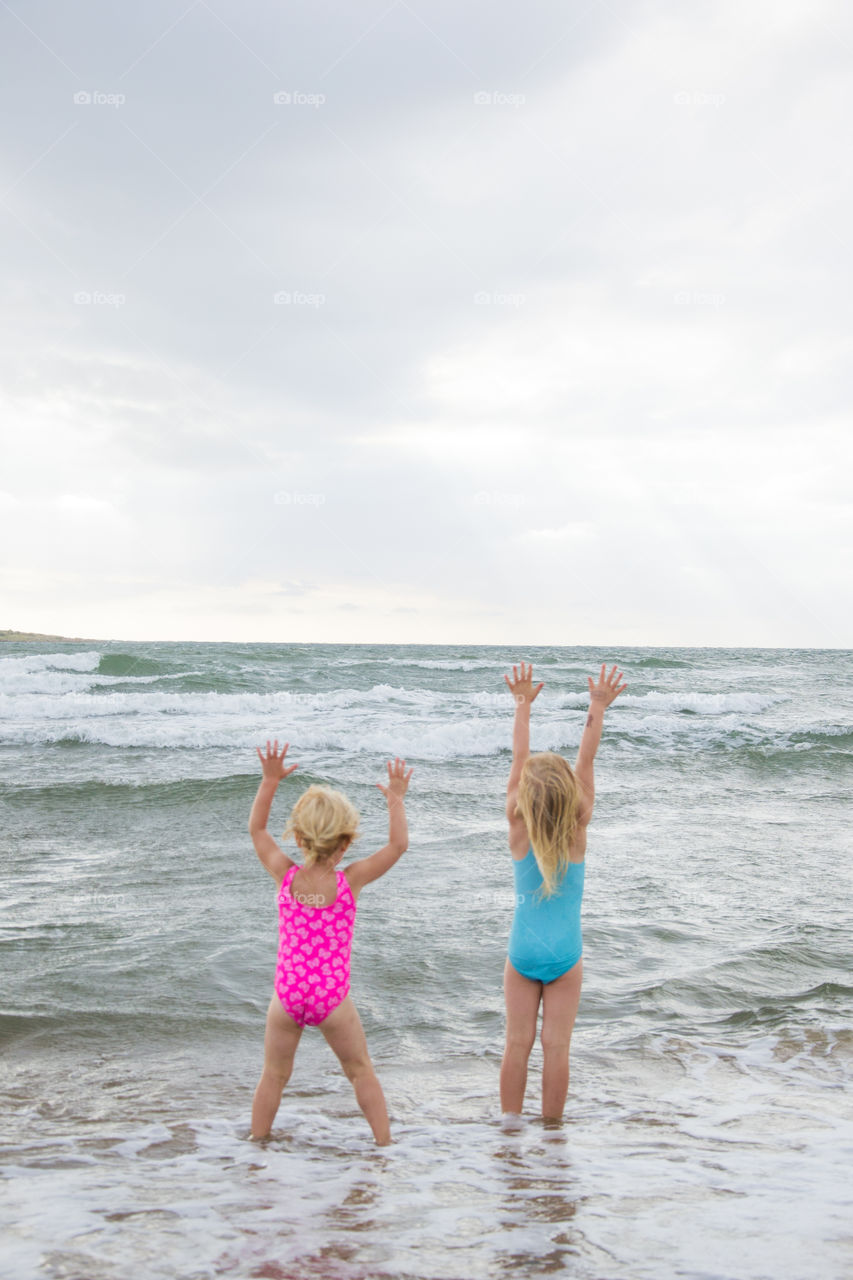 Twi sisters playing at the beach of Tylösand outside Halmstad in Sweden. It's about to get stormy weather but the girls is having fun swimming and playing in the water.
