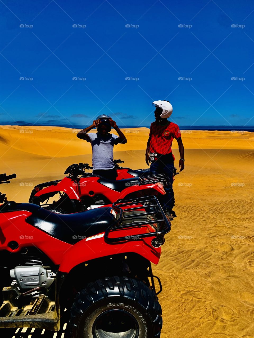 3 quad bikes on the dunes of the Namib desert with the view of the ocean in the background.