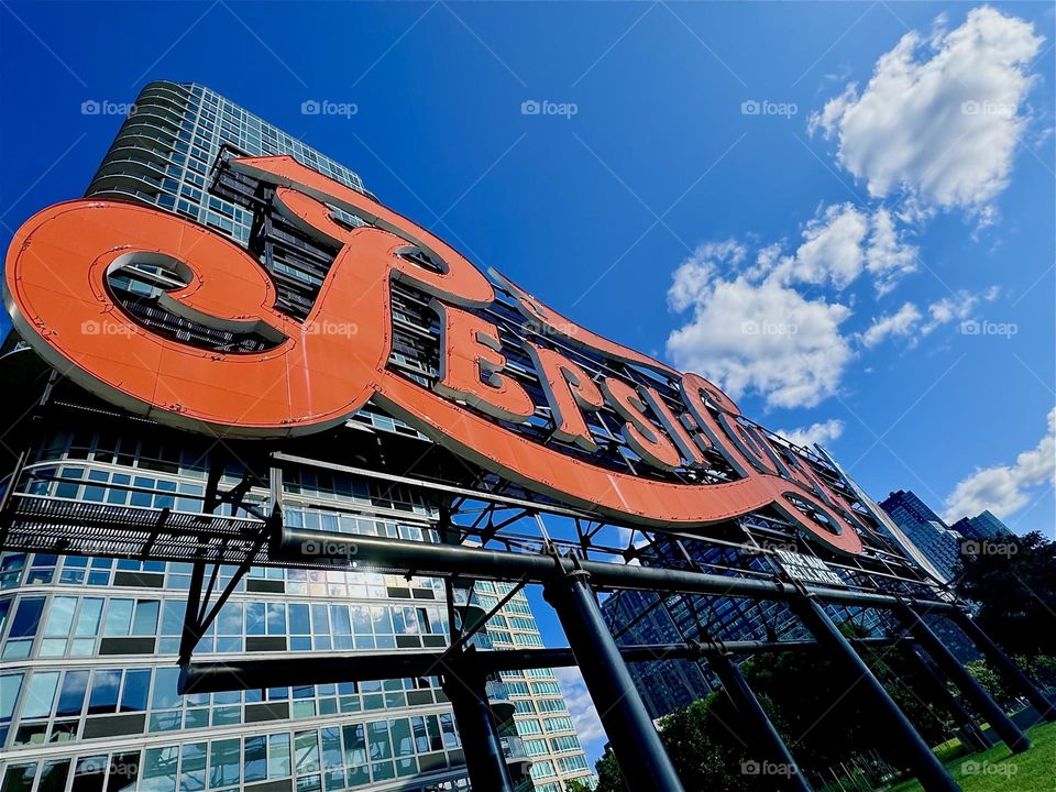 The “Art Deco” inspired “PEPSI COLA” sign adorns a city park high above the ground on a billboard so it can be seen from afar here on the “East River” near “Newtown Creek” in LIC, Queens. 2024. Hypnotic Productions