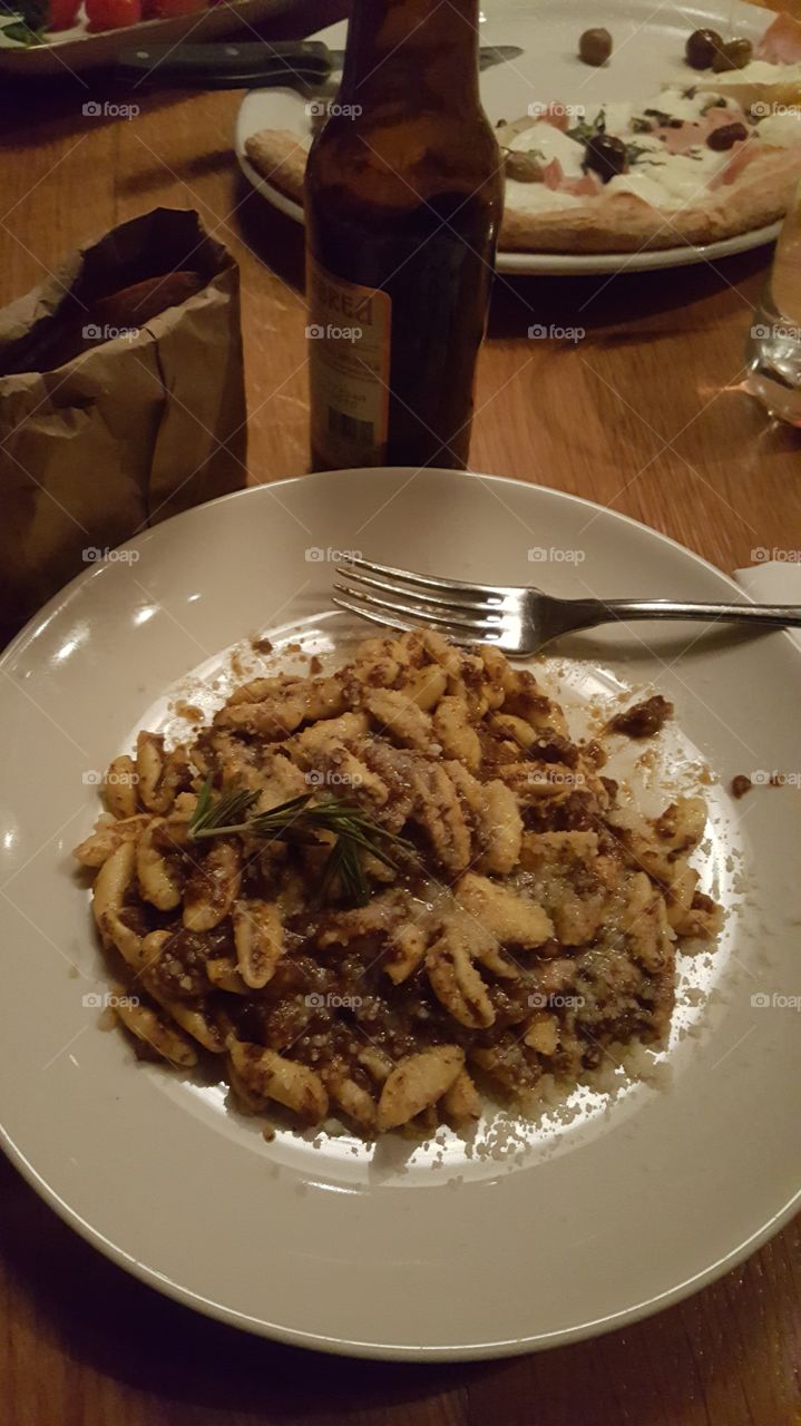 A delicious plate of egg pasta and wild boar, served with a bottle of beer