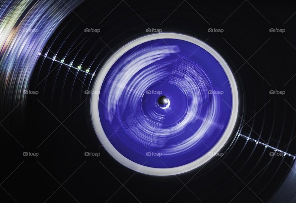 Spinning vinyl record with bright blue label and a spectrum of colours across the groves