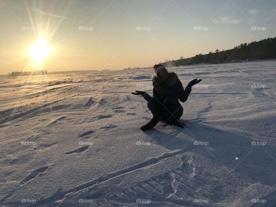 Sunset in winter on the sea.  The girl on the background of a winter sunset in Siberia.