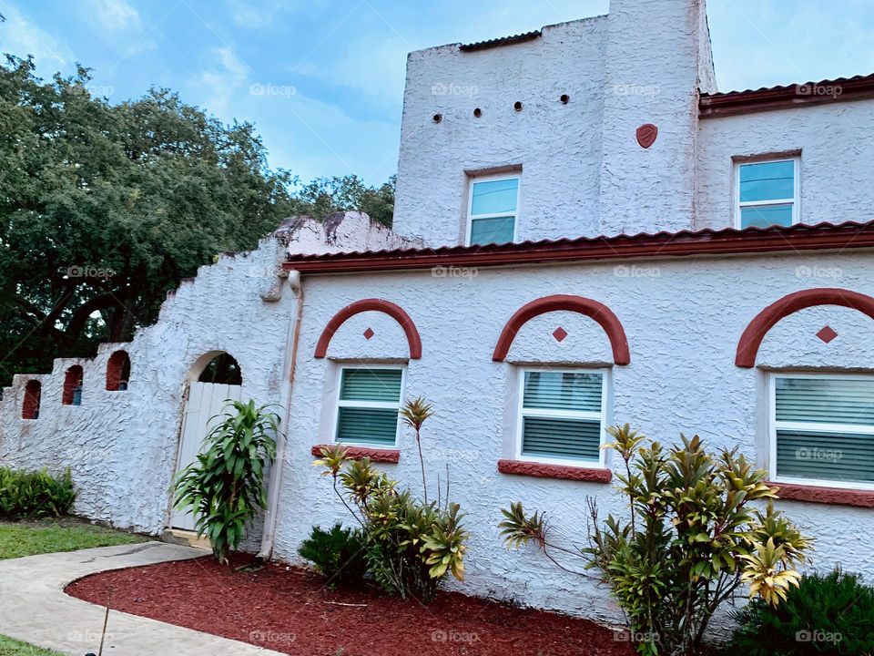 White and red spanish old style architecture residential large house built in the early 1900s. House front with nice plants arrangement, beautiful landscaping garden.