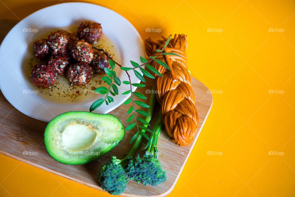 Cheese balls, avocado and cheese braid on yellow background