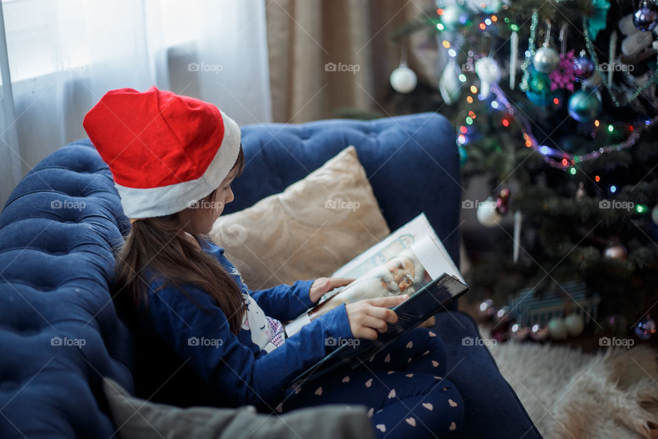 Little sisters reading a book at Christmas time 
