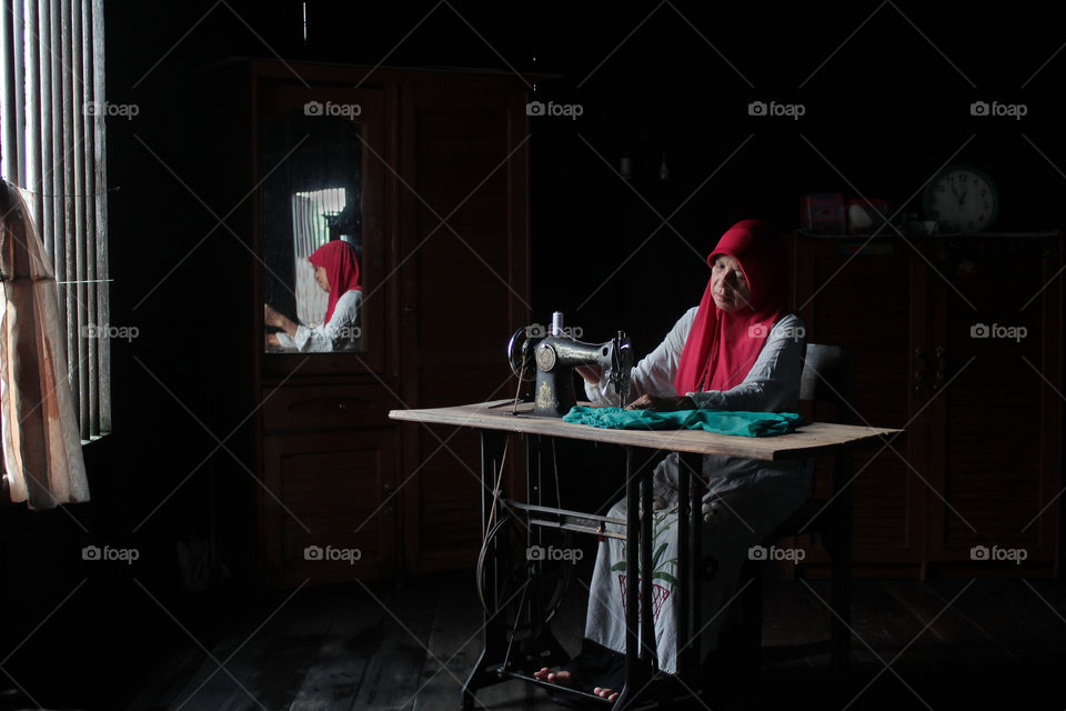 sewing in front of the window.