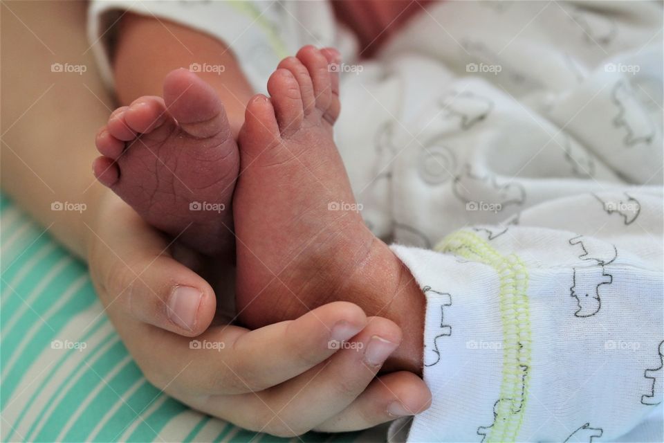 newborn feet being held by big sister