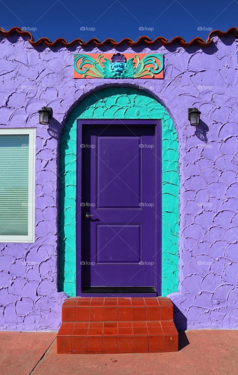 Purple door with turquoise arch on a purple stucco building of the Venetian court in Capitola California 