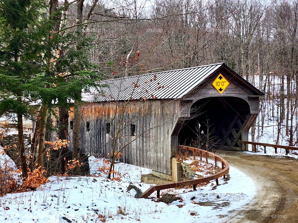 A single lane covered bridge endures another winter in New Hampshire and ensures safe passage over an icy river