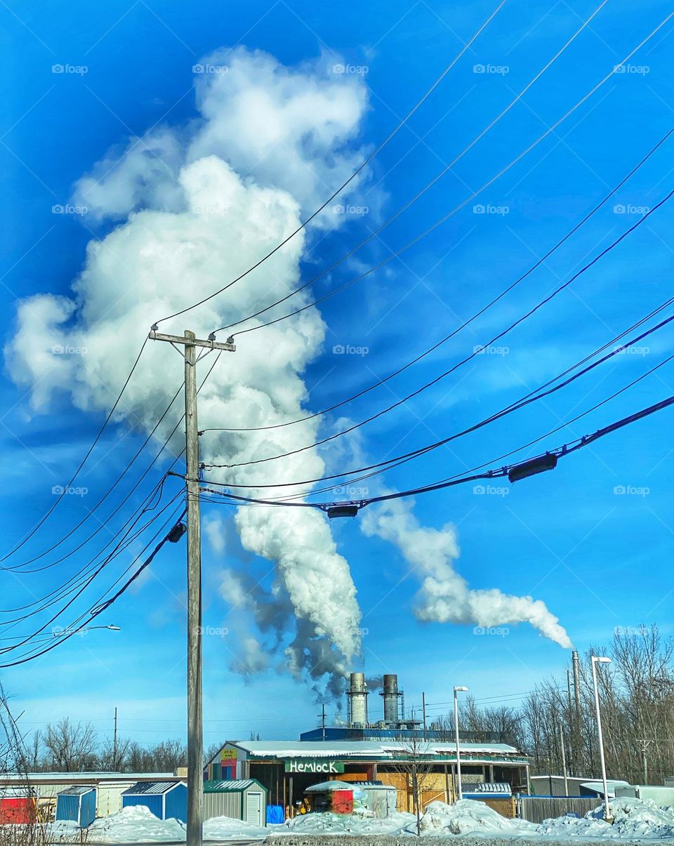 Hemlock sign on a building in front of a factory with smoke coming out of smokestacks 