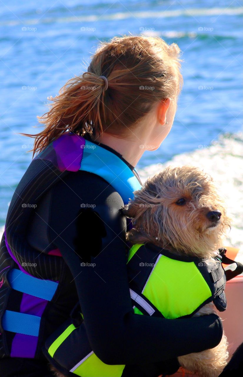 A young girl and her dog enjoy summer activities on the water while sporting colorful water gear