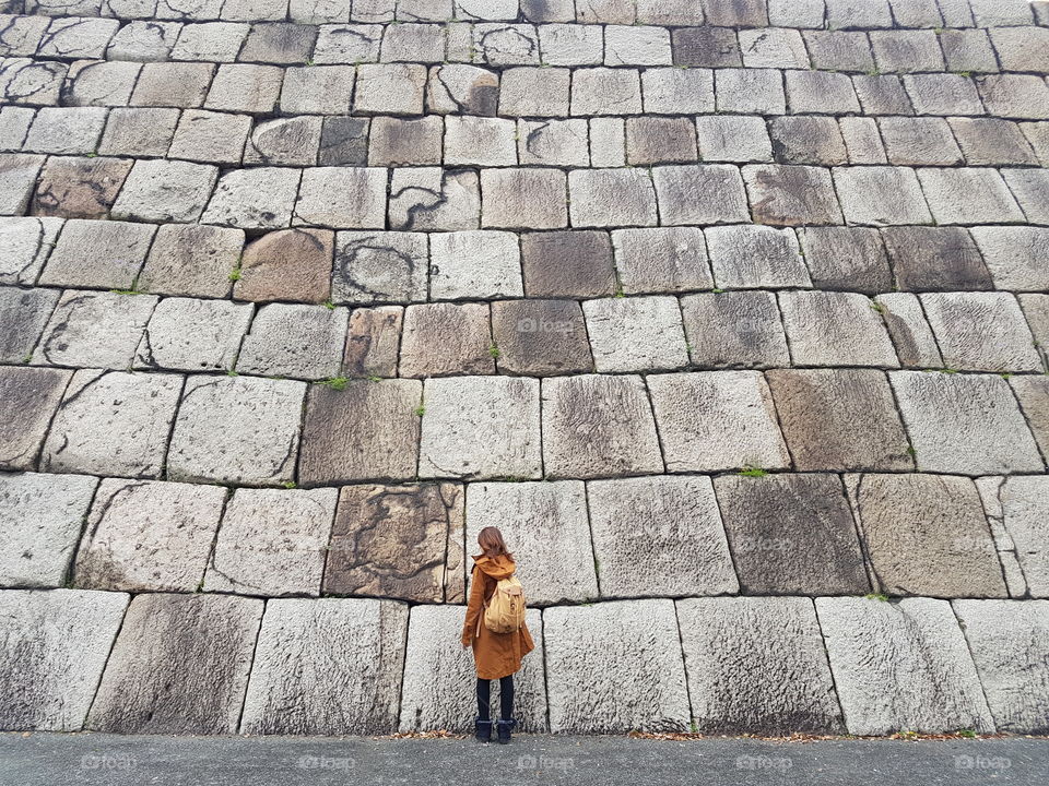 Rear view of a woman standing near the large block wall