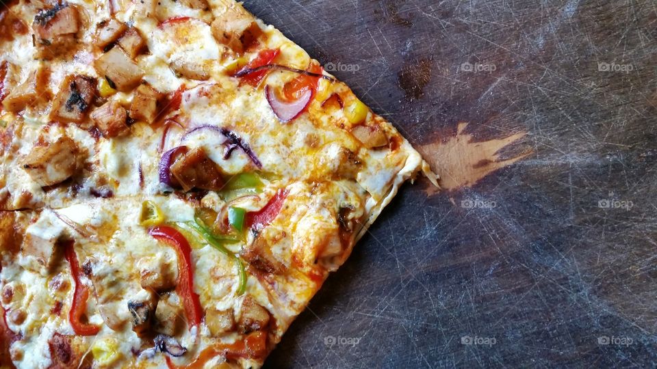 A big slice of pizza on a wooden board